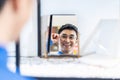 Smiling young asian man trying on new eyeglasses in the optical shop. Handsome man wearing new spectacles and looking at mirror, Royalty Free Stock Photo