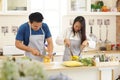 Smiling young Asian man and woman, perfectly happy couple preparing healthy food, lot of vegertable in the lovely modern kitche