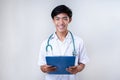 Smiling Young Asian medical doctor holding a medical report clipboard. Male doctor smiling holding clipboard Royalty Free Stock Photo
