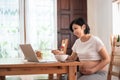 Smiling Young Asian Pregnant woman making video call on laptop in dining room Royalty Free Stock Photo