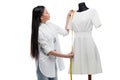 Smiling young asian tailor measuring stylish white dress on dummy