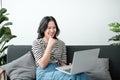 Smiling young asian teen girl video calling on laptop. Happy mixed race pretty woman student looking at computer screen Royalty Free Stock Photo