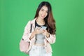 Smiling young Asian tourist girl with bag holding mobile smart phone ready to travel over green isolated background Royalty Free Stock Photo