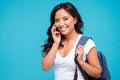 Smiling young asian woman with backpack talking on cellphone