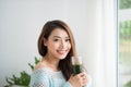 Smiling young asian woman drinking green fresh vegetable juice o Royalty Free Stock Photo