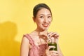 Smiling young asian woman drinking green fresh vegetable juice or smoothie from glass Royalty Free Stock Photo