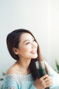 Smiling young asian woman drinking green fresh vegetable juice o Royalty Free Stock Photo