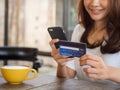 The smiling young Asian woman enjoys shopping online via a smartphone and paying online via credit card. Convenience of spending Royalty Free Stock Photo