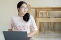 Smiling young Asian woman in glasses sit on floor and working on laptop or studying online at home Royalty Free Stock Photo