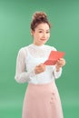 Smiling young Asian woman reading letter while standing green background Royalty Free Stock Photo