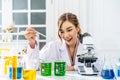 Smiling young asian woman wearing scientist uniform working at scientist laboratory with measuring liquid at laboratory Royalty Free Stock Photo