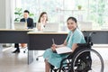 Smiling young Asian woman office worker in wheelchair holding pencil look at camera, disabled people working with colleague Royalty Free Stock Photo