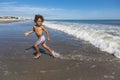 Smiling young b-racial boy running and playing at the beach while on a family vacation. Royalty Free Stock Photo