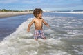 Smiling young b-racial boy running and playing at the beach while on a family vacation. Royalty Free Stock Photo