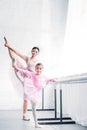 smiling young ballet teacher looking at little student stretching and looking at camera Royalty Free Stock Photo