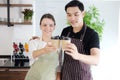 Smiling young barista couple loves Asian man and caucasian woman holding cups of hot coffee together. Start up Coffee shop and