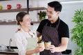 Smiling young barista couple loves Asian man and caucasian woman holding cups of hot coffee together. Start up Coffee shop and