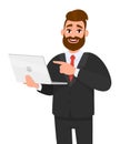 Smiling young bearded business man holding/showing latest brand new laptop computer device and pointing it with hand finger. Royalty Free Stock Photo
