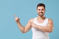 Smiling young bearded guy 20s in white singlet posing isolated on pastel blue background studio portrait. Sport fitness