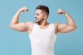 Smiling young bearded guy 20s in white singlet posing isolated on pastel blue wall background studio portrait. Sport