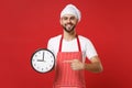 Smiling young bearded male chef cook or baker man in striped apron white t-shirt toque chefs hat isolated on red Royalty Free Stock Photo