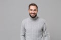 Smiling young bearded man in gray sweater posing isolated on grey wall background, studio portrait. Healthy fashion Royalty Free Stock Photo