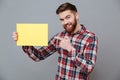Smiling young bearded man holding copyspace blank