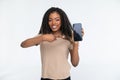 Smiling young beautiful African American woman wearing yellow sweater against white wall showing and pointing at empty phone Royalty Free Stock Photo