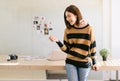 Smiling young beautiful Asian female blogger photographer standing in front of her desk at a bright home office studio. Happy Royalty Free Stock Photo