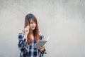 Smiling young beautiful asian woman thinking with writing book on concrete wall background. Vintage effect style pictures