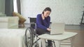 Portrait of a smiling young beautiful disabled woman in a wheelchair, working at home on a laptop, remote work Royalty Free Stock Photo