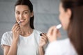 Smiling beautiful lady apply lipstick on lips looking in mirror Royalty Free Stock Photo