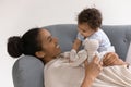 Smiling young biracial mom relax on couch with little baby Royalty Free Stock Photo