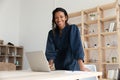 Smiling young biracial woman standing at table with computer.