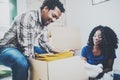 Smiling young black african couple moving boxes into new home together and making a successful life.Cheerful family