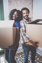 Smiling young black african couple moving boxes into new home together and making a successful life.Cheerful family
