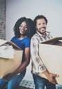 Smiling young black african couple moving boxes into new home together and making a successful life.Cheerful family