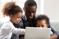 Smiling young black dad play on laptop with kids Royalty Free Stock Photo