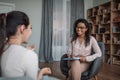 Smiling young black female doctor psychologist consulting european woman in modern clinic interior