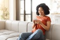 Smiling Young Black Female Relaxing With Her Smartphone On Couch At Home Royalty Free Stock Photo