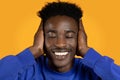 Smiling young black guy with closed eyes covering his ears Royalty Free Stock Photo