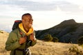 Smiling young black man hiking in mountains with backpack bag