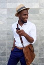 Smiling young black man with mobile phone and bag Royalty Free Stock Photo