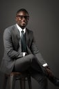 Smiling young black man sits with glasses and gray business suit Royalty Free Stock Photo