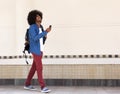 Smiling young black man walking with bag and mobile phone Royalty Free Stock Photo