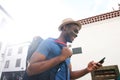 Smiling young black man walking with cellphone and bag Royalty Free Stock Photo