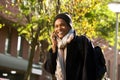 Smiling young black man walking in city with mobile phone and bag during autumn Royalty Free Stock Photo