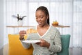 Smiling young black woman having breakfast at home, eating croissant Royalty Free Stock Photo