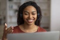 Smiling young black woman with headset communicating by video call on laptop Royalty Free Stock Photo