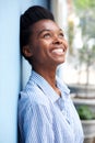 Smiling young black woman leaning against wall and looking up Royalty Free Stock Photo